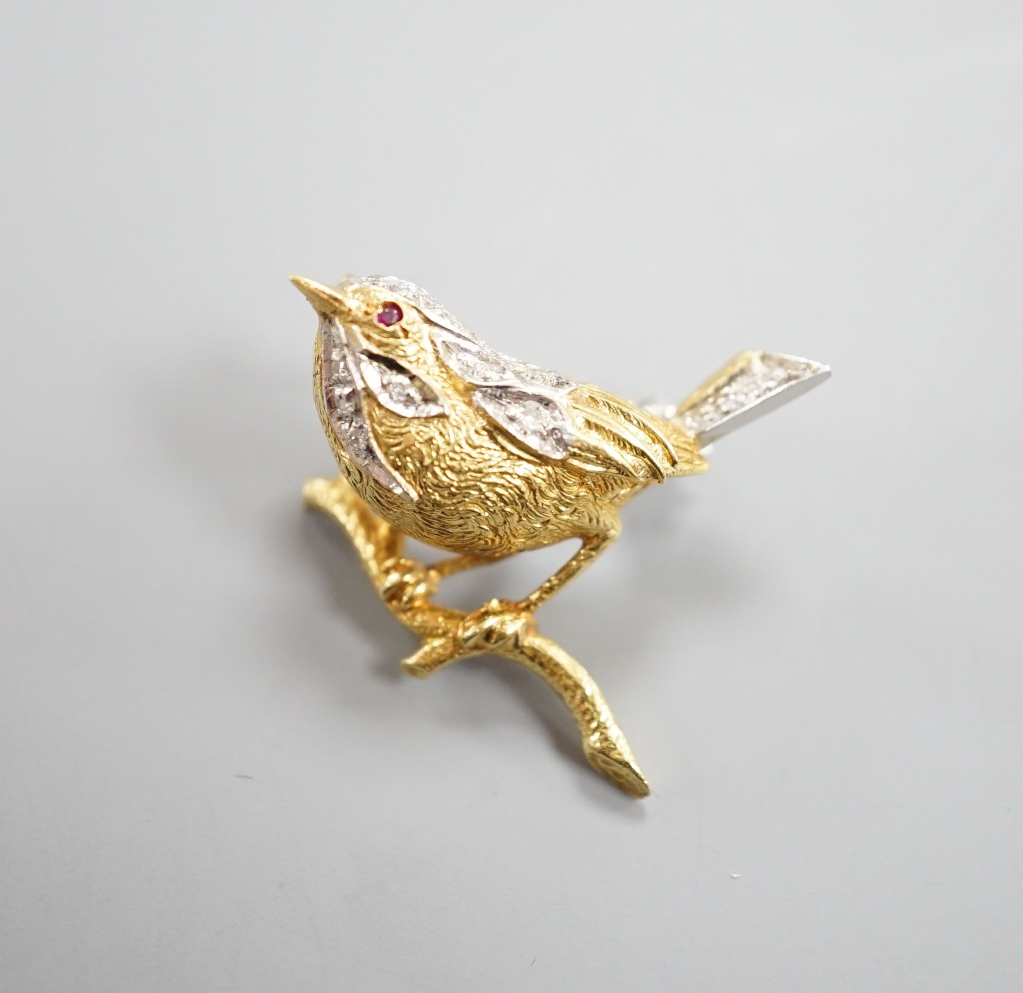 A modern textured 18ct two colour gold, ruby and diamond set bird brooch, 24mm, gross weight 6 grams.